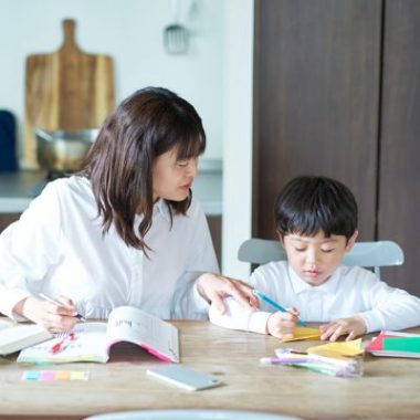 Child working on homework at kitchen table with parent support.