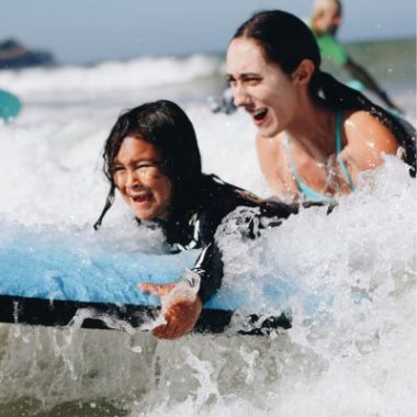 A Los Courage Camps staff member teaches a child how to surf.