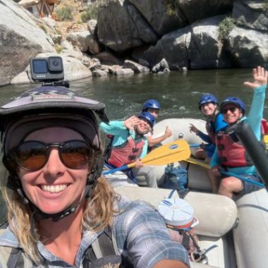 A family wearing helmets and life jackets smiles from an inflatable raft during a guided rafting trip on California's Kern River near Kernville.