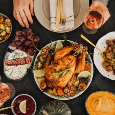 A thanksgiving spread with a turkey, sides, wine and desserts.