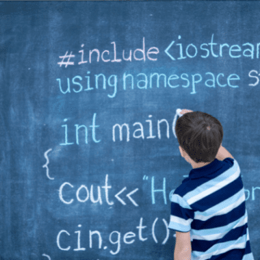 A boy writes coding instructions on a blackboard.